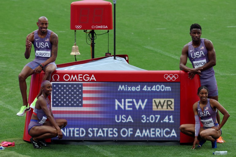 Paris 2024 Olympics - Athletics - 4 x 400m Relay Mixed Round 1 - Stade de France, Saint-Denis, France - August 02, 2024. Kaylyn Brown of United States, Bryce Deadmon of United States, Shamier Little of United States and Vernon Norwood of United States pose with a time board as they celebrate after setting a new world record and winning heat 1. REUTERS/Phil Noble