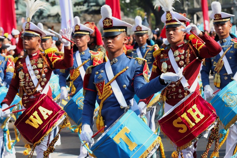 Military bands marching. They have colourful drums and sashes.