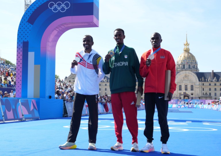 Aug 10, 2024; Paris, France; Gold medalist Tamirat Tola (ETH), silver medalist Bashir Abdi (BEL) and bronze medalist Benson Kipruto (KEN) at the medal ceremony after the men's marathon during the Paris 2024 Olympic Summer Games in front of the Invalides. Mandatory Credit: Kirby Lee-USA TODAY Sports