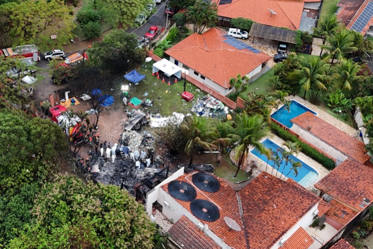 A drone view shows people working at the site of a plane crash in Brazil