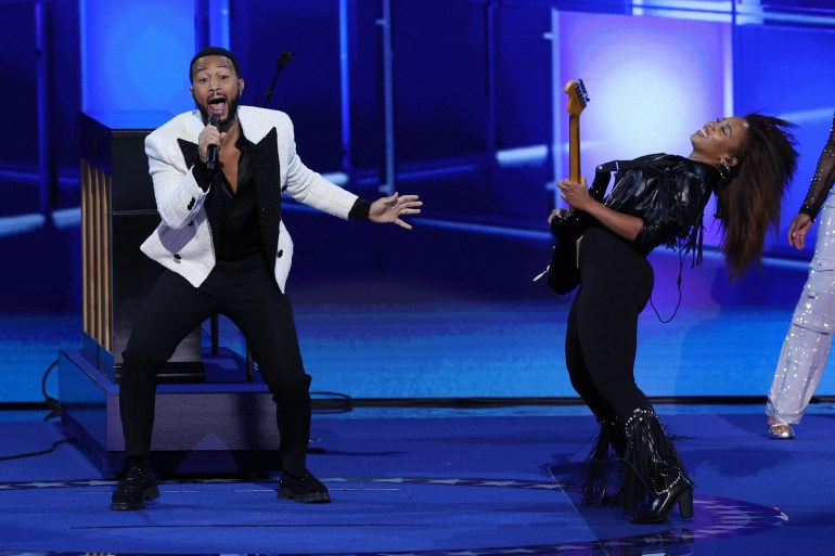 John Legend and Sheila E performing at the DNC. He is singing and she is playing guitar.