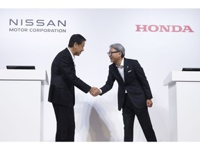 Makoto Uchida and Toshihiro Mibe shake hands prior to a joint news conference in Tokyo on Aug. 1.