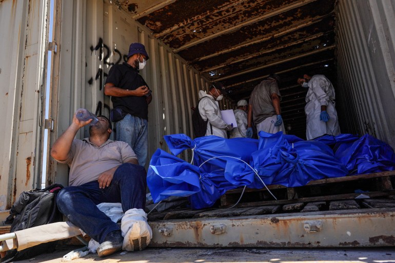 Men prepare to remove bodies from a container after they were taken and later released by Israel, ahead of a mass funeral at a cemetery in Khan Yunis in the southern Gaza Strip on August 5, 2024, amid the ongoing conflict between Israel and the Palestinian Hamas militant group. (Photo by Bashar TALEB / AFP)