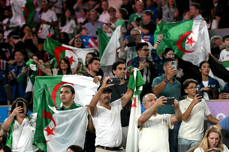 Fans of Algeria's Imane Khelif cheer her on during the women's 66kg semi-final boxing match during the Paris 2024 Olympic Games at the Roland-Garros Stadium, in Paris on August 6, 2024. (Photo by MOHD RASFAN / AFP)