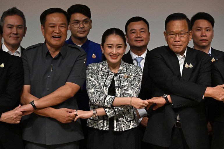 Paetongtarn Shinawatra with members of the ruling coalition. They are locking arms.