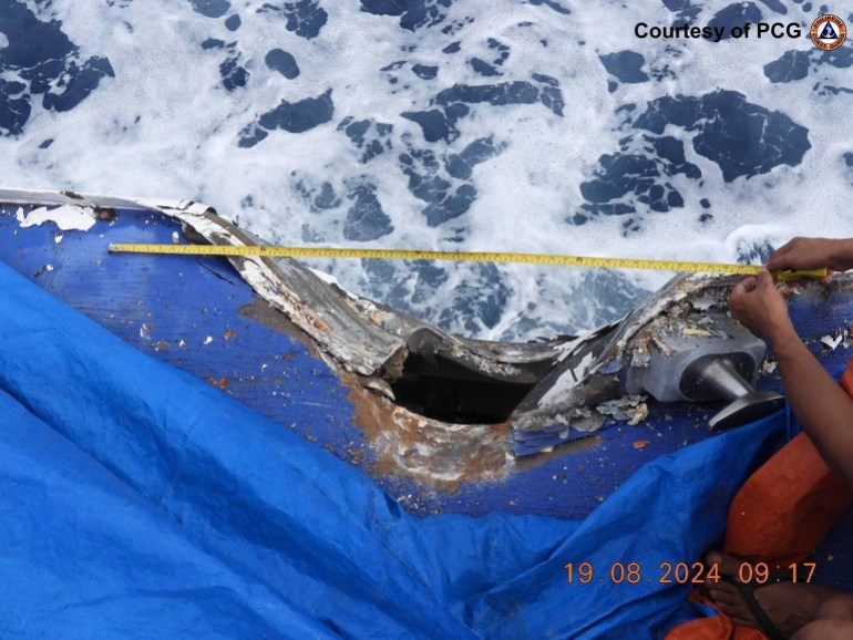 a sailor holding a measuring take across a large hole on a Philippines coast guard ship