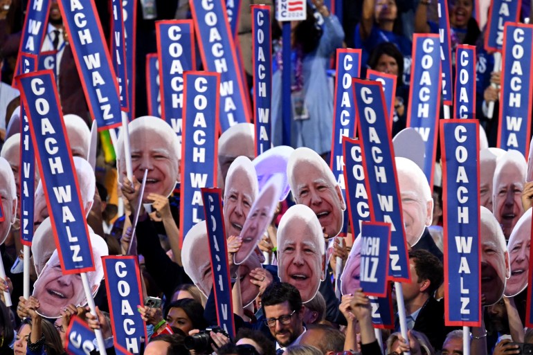 People at the DNC holding banners reading Coach Walz. They are also holding cutouts of his face