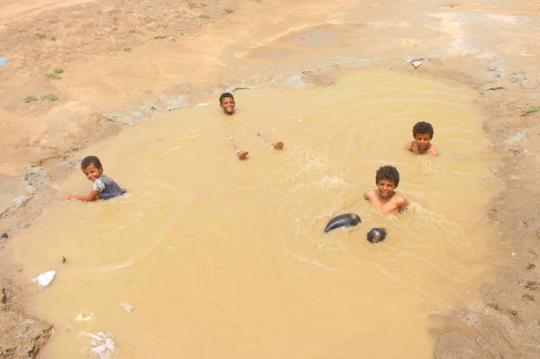 Boys bathe in a large water puddle left after heavy rains near a camp for people displaced by conflict in Yemen's Hajjah province