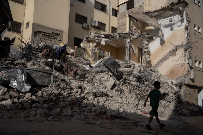 a child can be seen in the foreground in front of a destroyed building