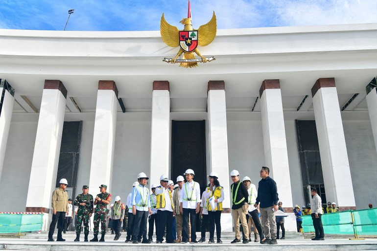 Joko Widodo outside the presidential palace. He is on an inspection tour and wearing a white hard hat. Others are also wearing hard hats.