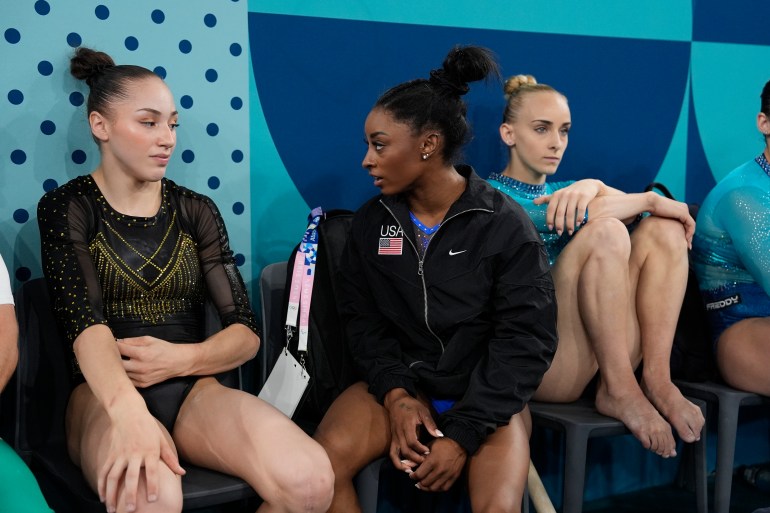 Kaylia Nemour, left, of Algeria, and Simone Biles, of the United States, speak during the women's artistic gymnastics all-around finals in Bercy Arena at the 2024 Summer Olympics, Thursday, Aug. 1, 2024, in Paris, France. (AP Photo/Charlie Riedel)