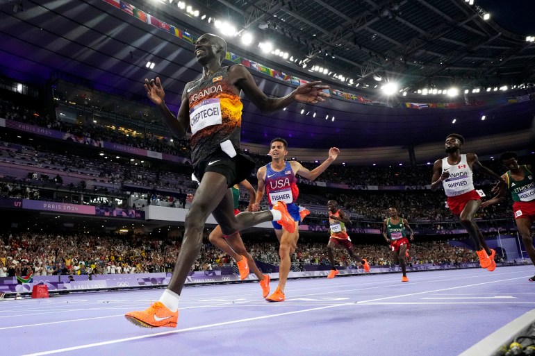 Joshua Cheptegei, of Uganda, celebrates after winning the men's 10,000-meter final at the 2024 Summer Olympics, Friday, Aug. 2, 2024, in Saint-Denis, France. (AP Photo/David J. Phillip)