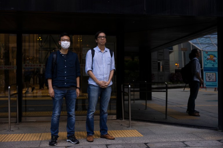 Former chief editor Chung Pui-kuen on the right, and former acting editor Patrick Lam on the left. Chung is wearing jeans and a pale blue shirt, Lam is in jeans and a navy blue shirt. Both men are wearing glasses. Chung looks serious. Lam is wearing a mask. 