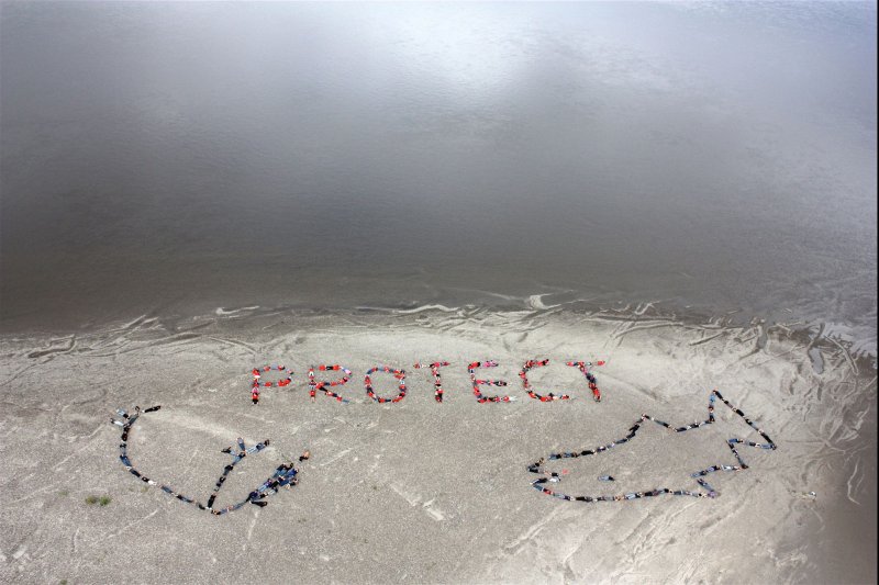 Arctic native people of the Gwich'in Nation form a human banner on the banks of the Porcupine River near Fort Yukon, Alaska, with a message to protect the Arctic National Wildlife Refuge from oil development in 2010. On Thursday, NOAA announced a $105 million investment to restore salmon in Alaska waters that Indigenous communities subsist on. File Photo by Camila Roy/UPI