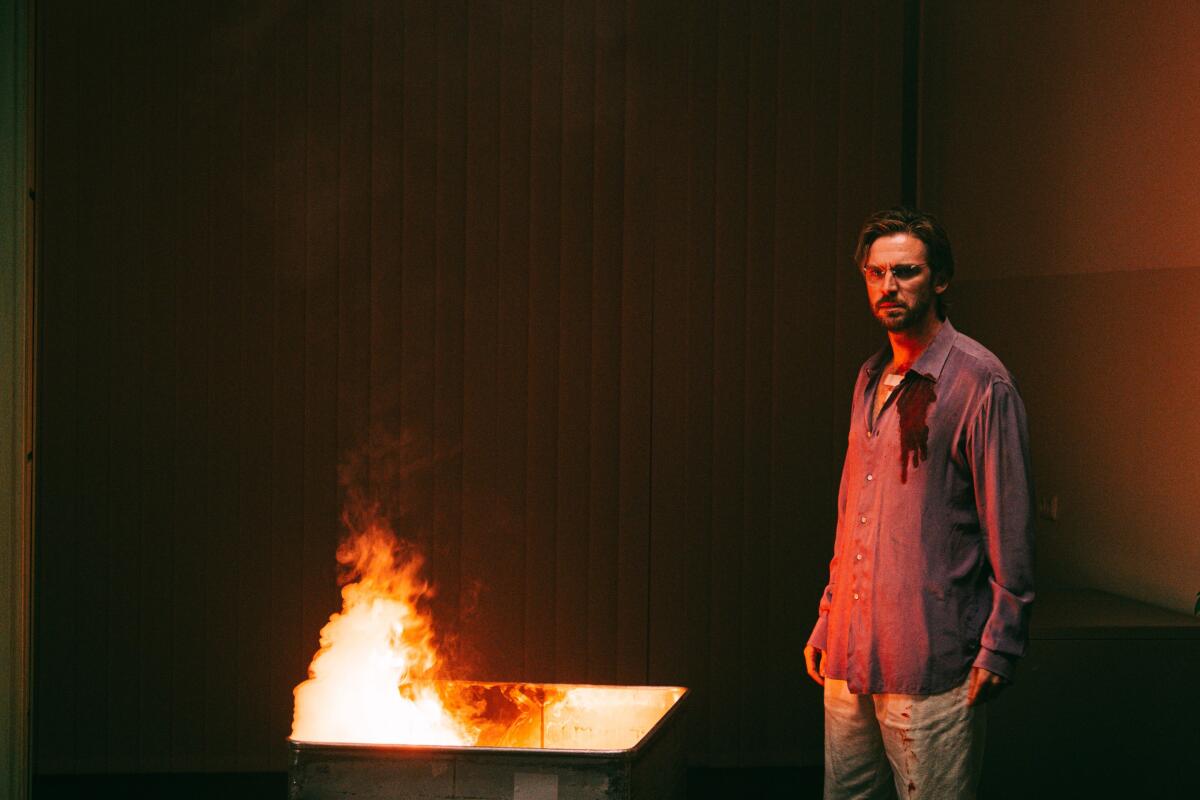 An ominous man stands by a burn box.