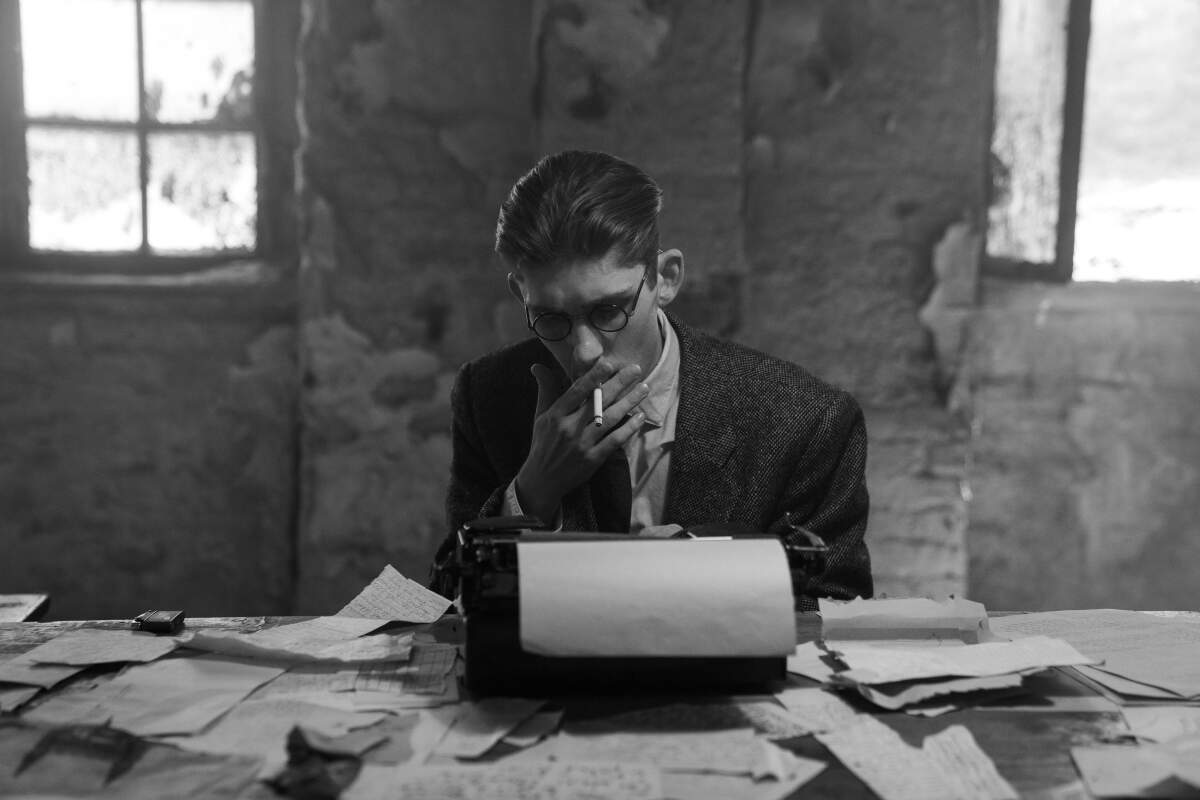 A young man smokes at a typewriter.