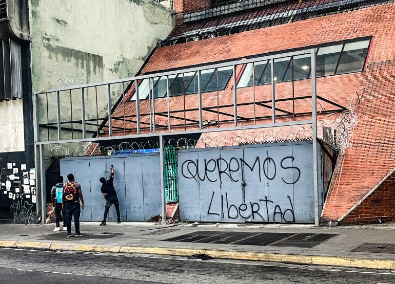 Graffiti painters spray "Queremos Libertad" on a wall outside in Caracas.