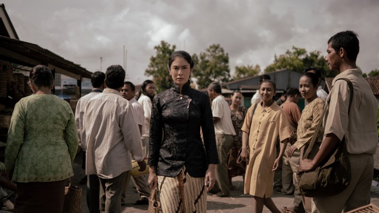 A still from the Netlfix drama Gadis Kretek (Cigarette Girl). It shows Dasiyah, the character played by Dian Sastrowardoyo, walking out of a crowd. She looks determined.