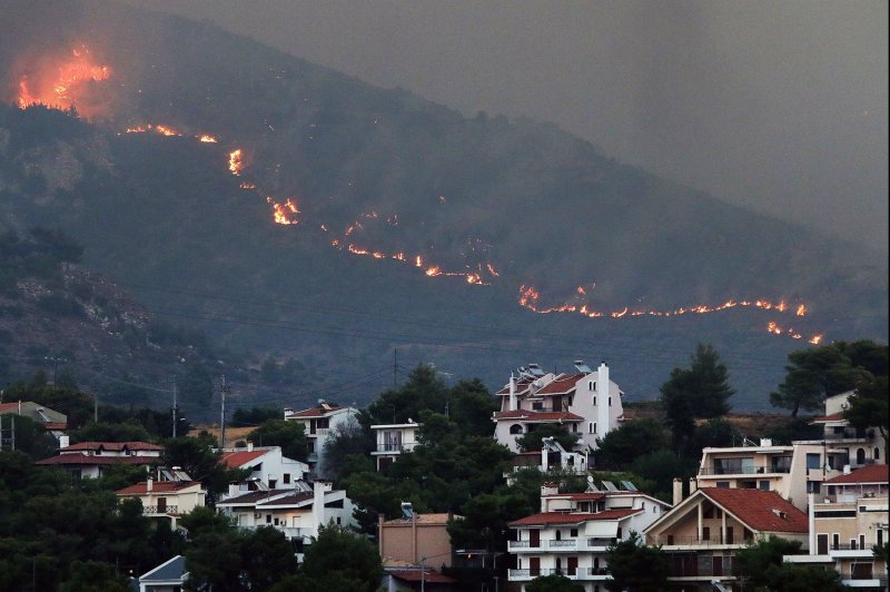 A wildfire approaches houses at Penteli mount northeast of Athens on Mnday, defying desperate efforts by firefighters to halt the flames. Auhtorities said it was headed toward Penteli fanned by strong winds and scroching temperatures having raced across the Penteli mountain range overnight. Photo by George Vitsaras/EPA-EFE