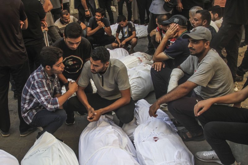 People sit near the bodies of a family members at the al-Maamadani hospital, following an Israeli strike that killed more than 100 people on a school sheltering displaced Palestinians. a medical source said, in Gaza City, on Saturday on August 10, 2024. Photo by Mahmoud Zaki/UPI