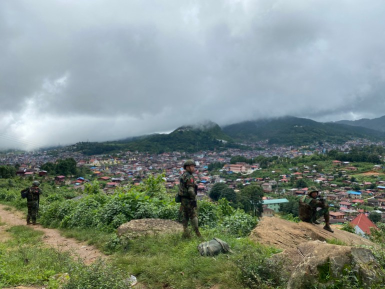 Soldiers standing on a hill. They are looking down on the town of xxx