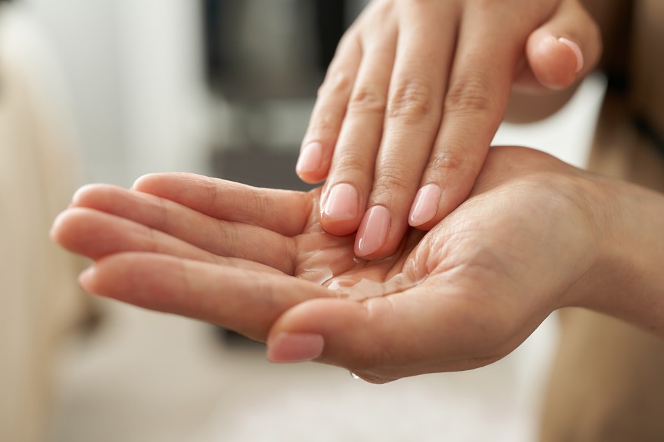 A woman rubs body oil in her hands (stock photo)