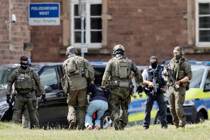 Police officers on Sunday lead the Solingen knife attack suspect out of the helicopter to his arraignment at the Federal Supreme Court in Karlsruhe, Germany. Photo by Ronald Wittek/EPA-EFE