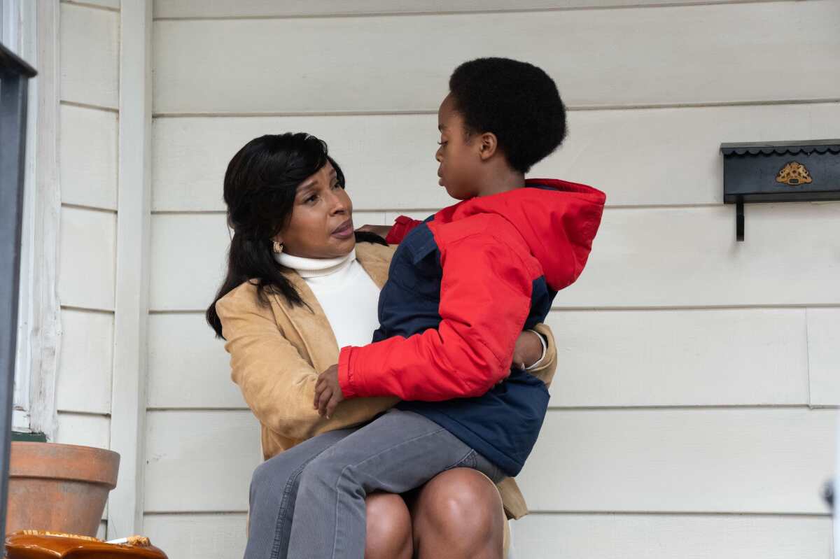 A mother speaks to her young son seated on her lap.