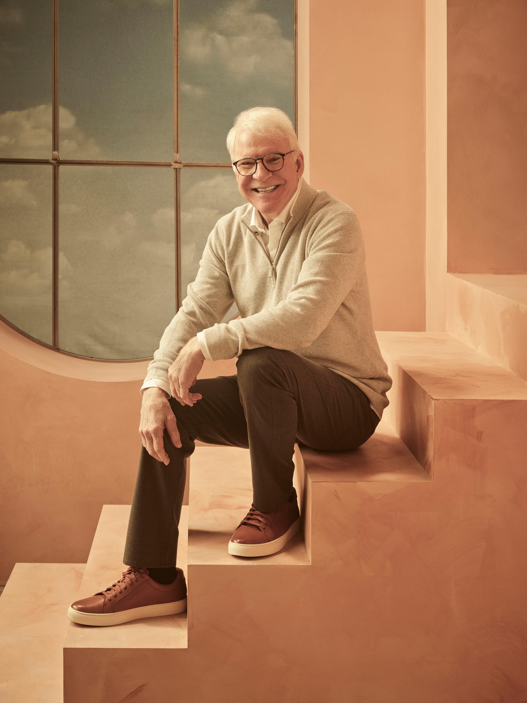 Steve Martin sitting on some steps in a studio. (Mark Seliger / Disney)