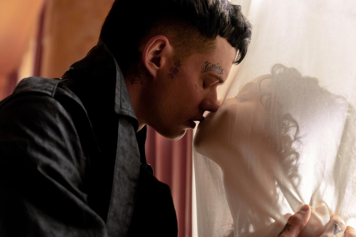 A man kisses a woman whose face is behind a white gauzy curtain.