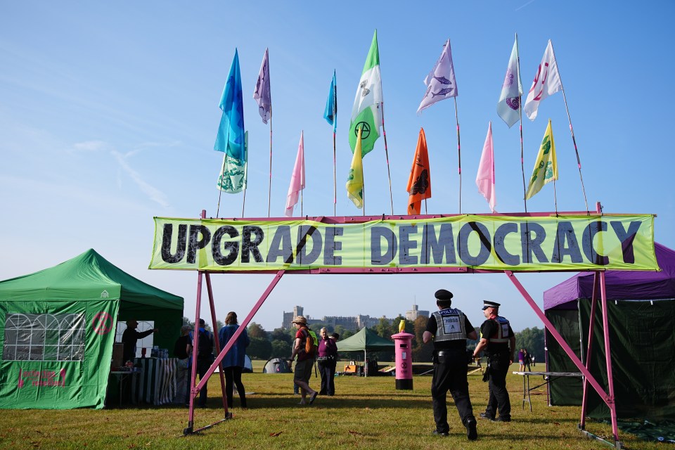 Police officers walk beneath a banner reading 'upgrade democracy'