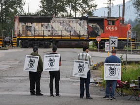 Locked-out Canadian National Railway workers stand at a picket line in Surrey, B.C., on Thursday.