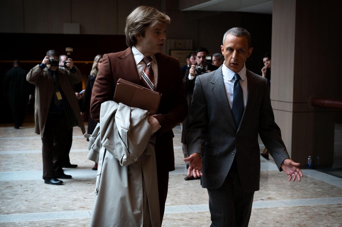 Two men in suits walk in a corridor.