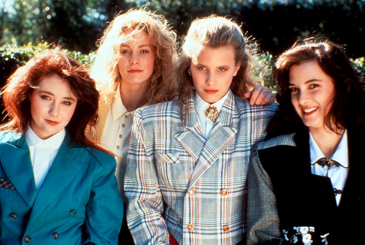 Four young women pose in suit jackets for the camera in the '80s.