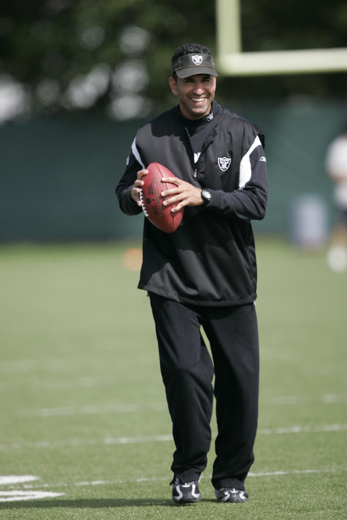 Oakland Raiders receiver's coach Sanjay Lal holds a football during training camp in Alameda in 2009.