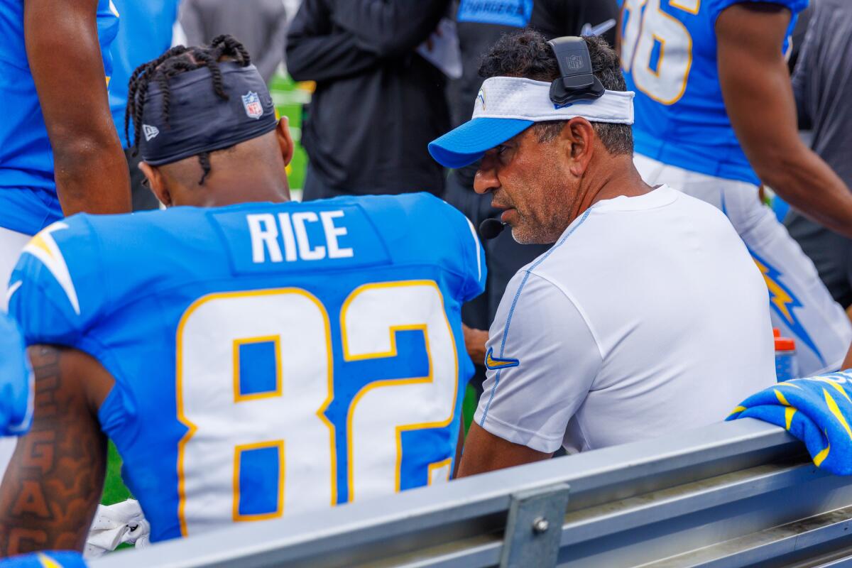 Chargers wide receivers coach Sanjay Lal speaks with Brenden Rice on the bench during a preseason game.