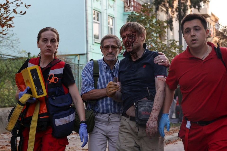 An injured man walks with paramedics after getting rescued from a residential building damaged during Russia's attack on Wednesday