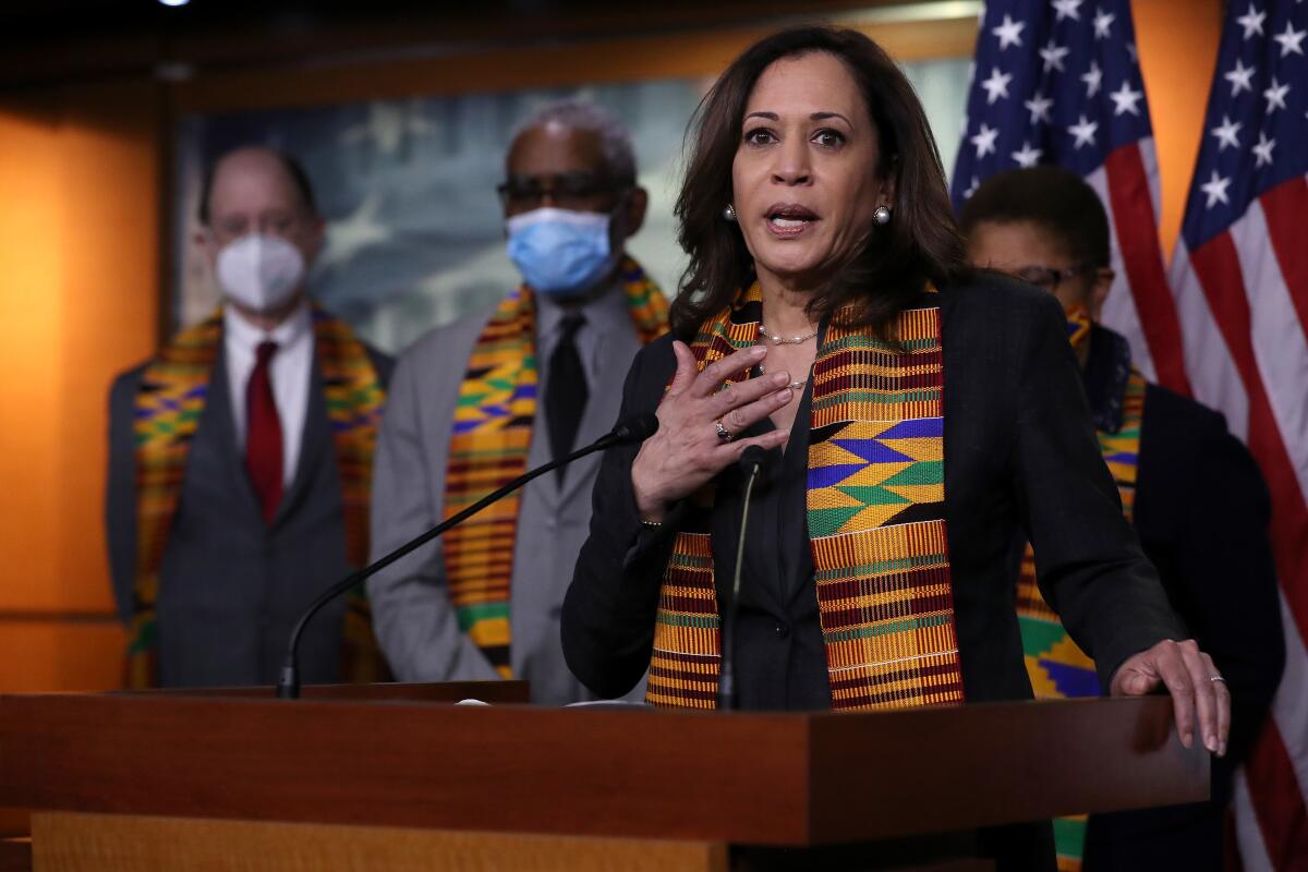 Then-Sen. Kamala Harris speaks at a microphone as fellow Democrats stand behind her