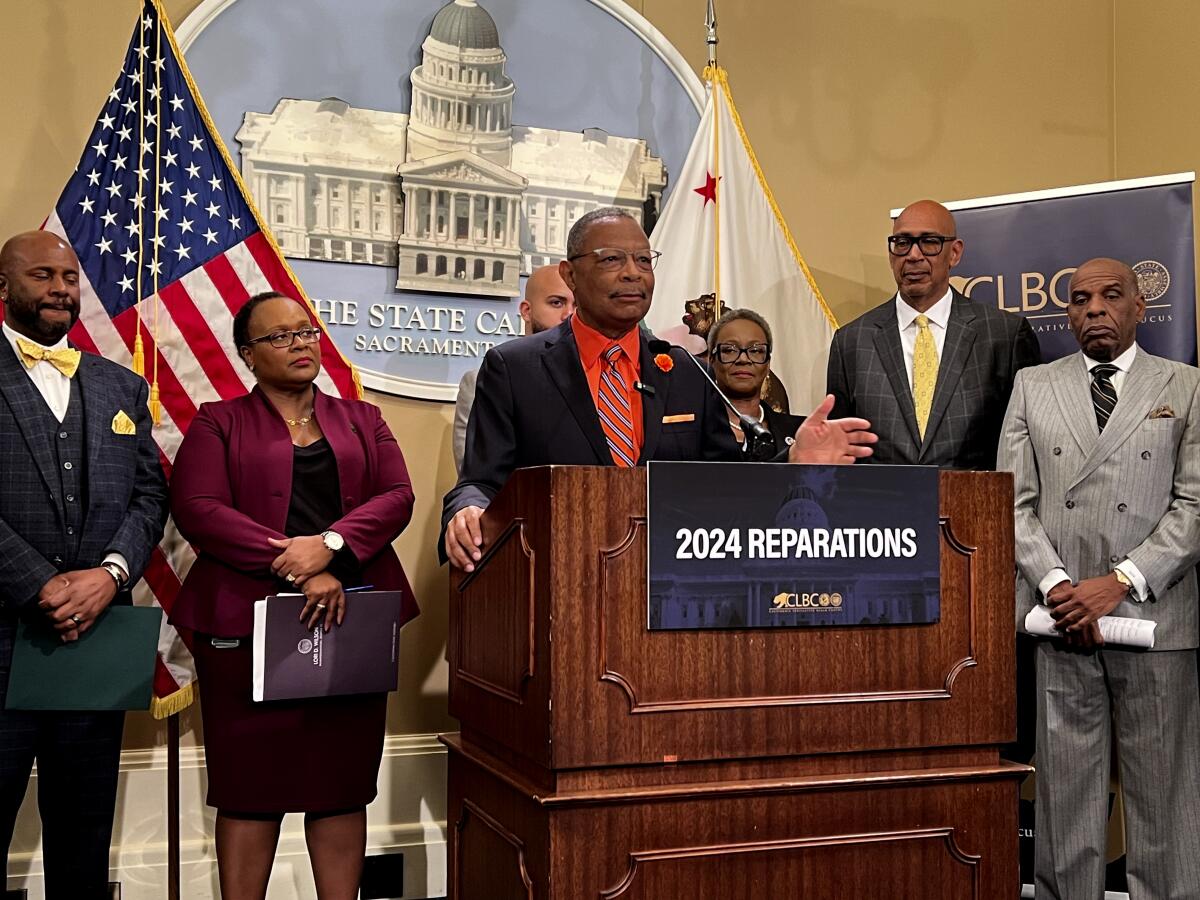 Assemblymember Reggie Jones-Sawyer speaking at a lectern, surrounded by others