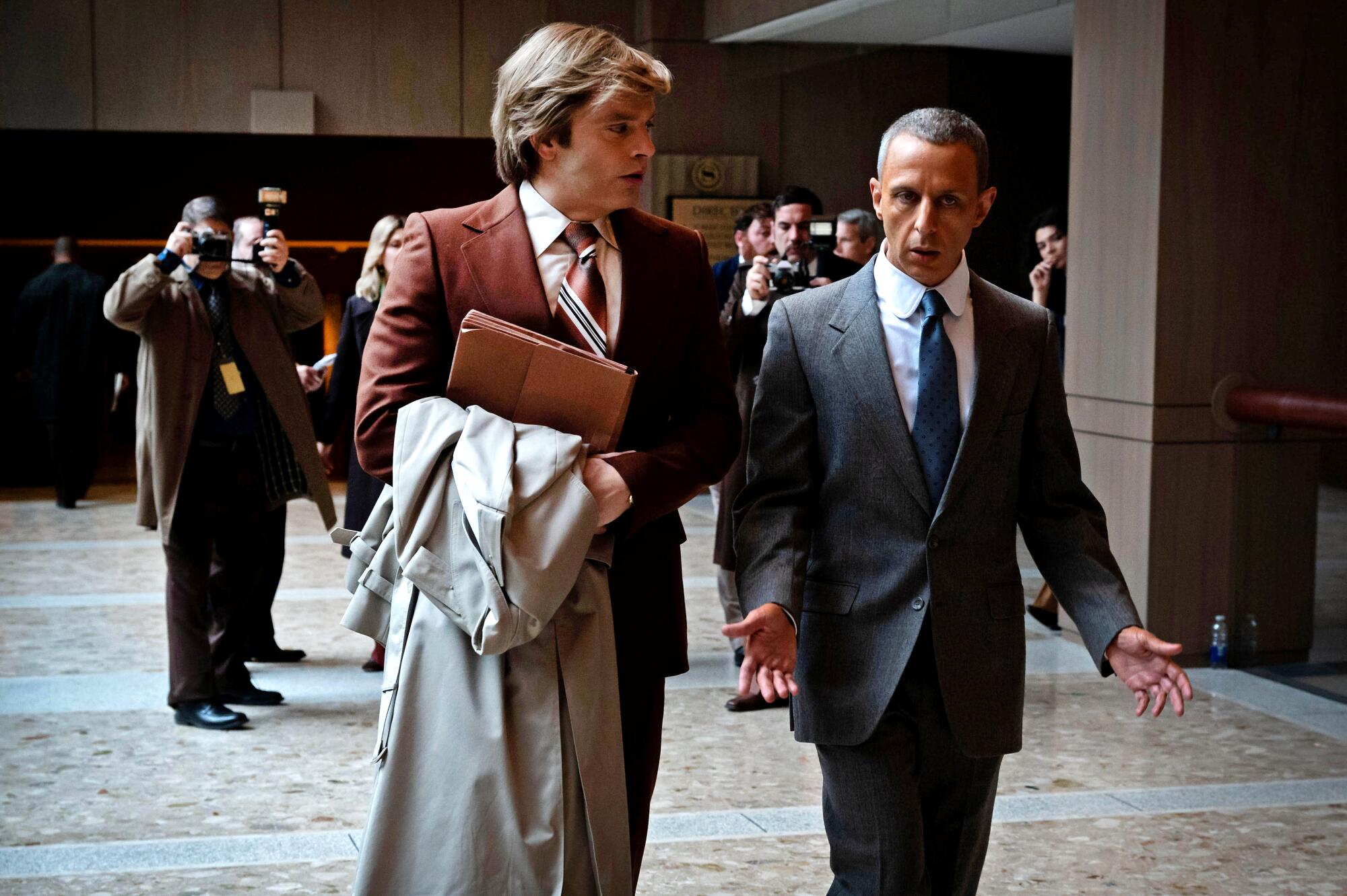 Two men in suits walk in a lobby.