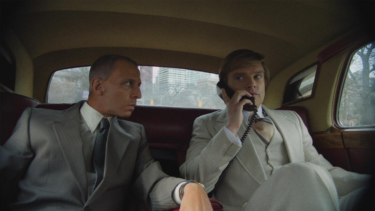 Two men ride in the back seat of a limo.