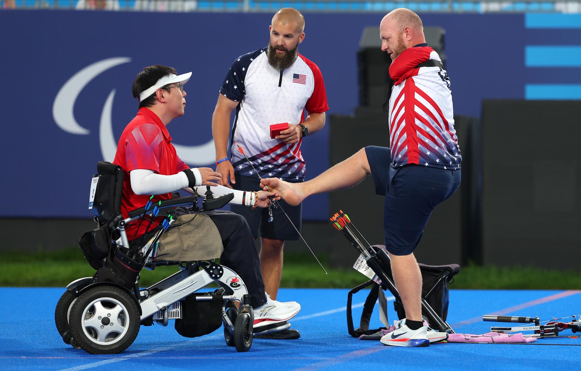 Matt Stutzman presents an arrow to Chinese rival He Zihao at 2024 Paralympics.