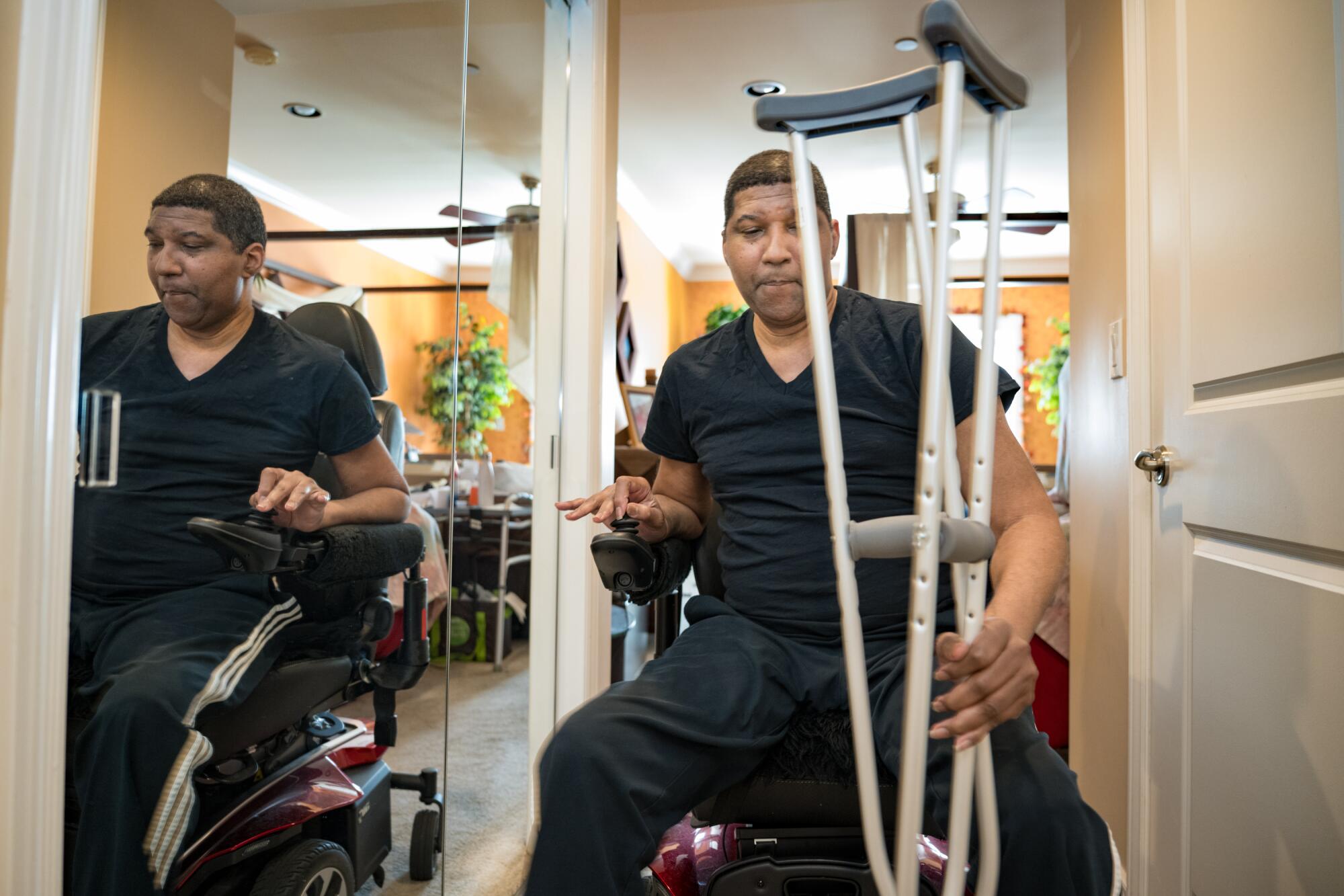 A man in a wheelchair holds onto crutches.