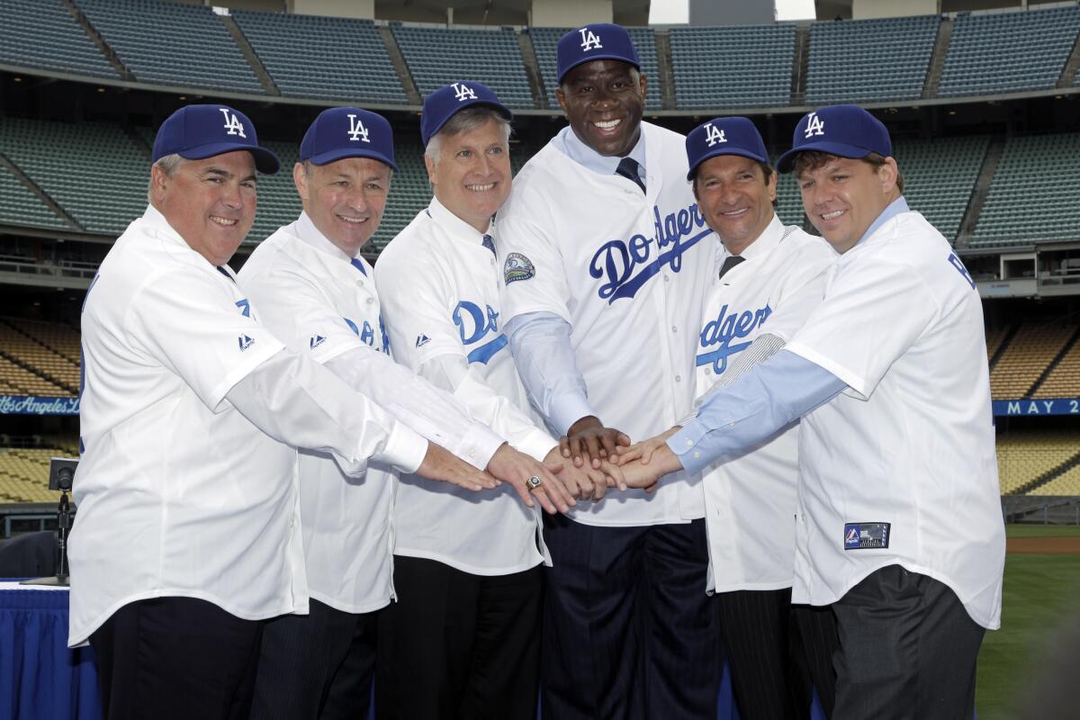 A group of men in Dodgers jerseys put their hands together.