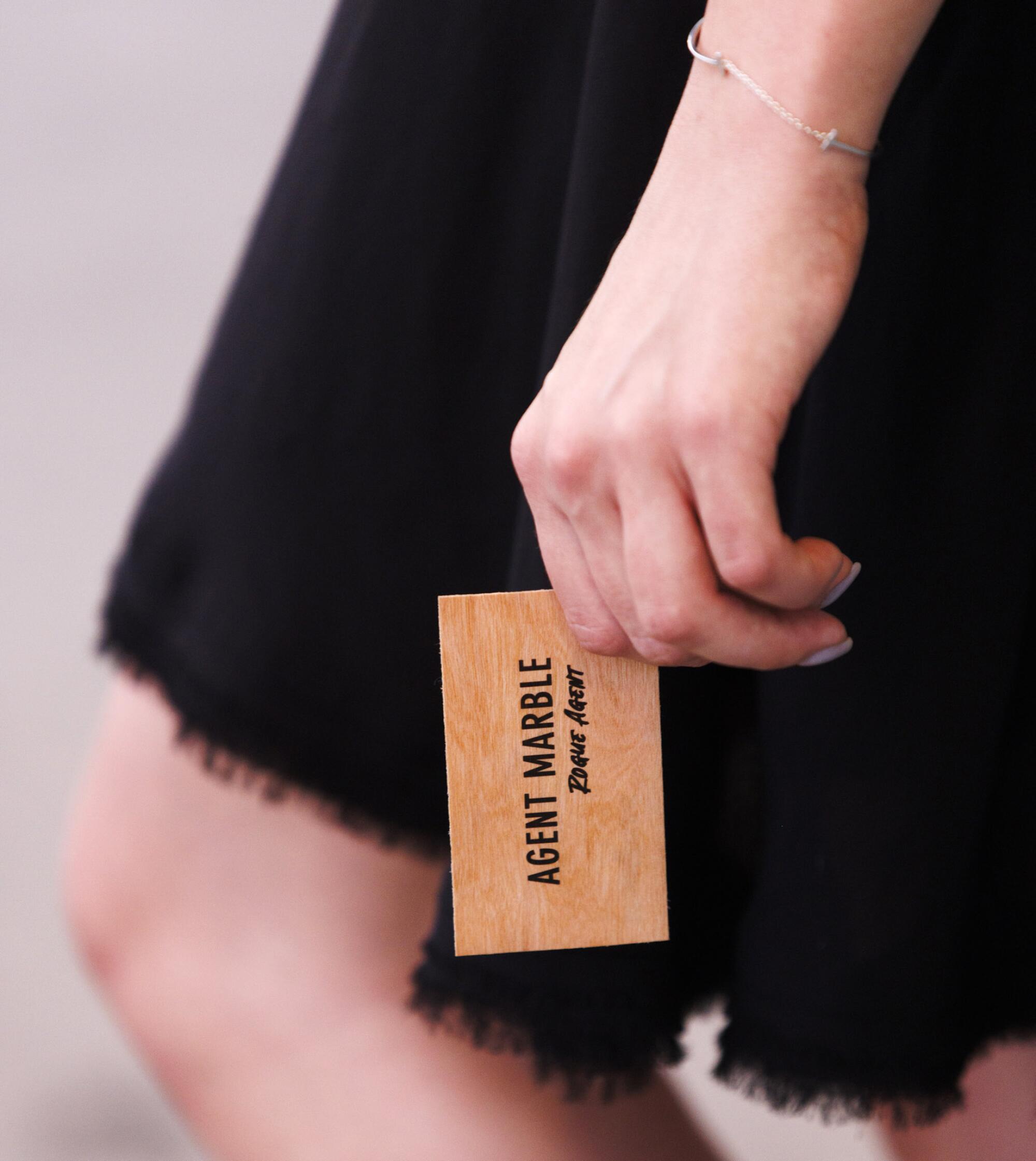 A hand holds a business card printed with the words "Agent Marble" and "Rogue agent"