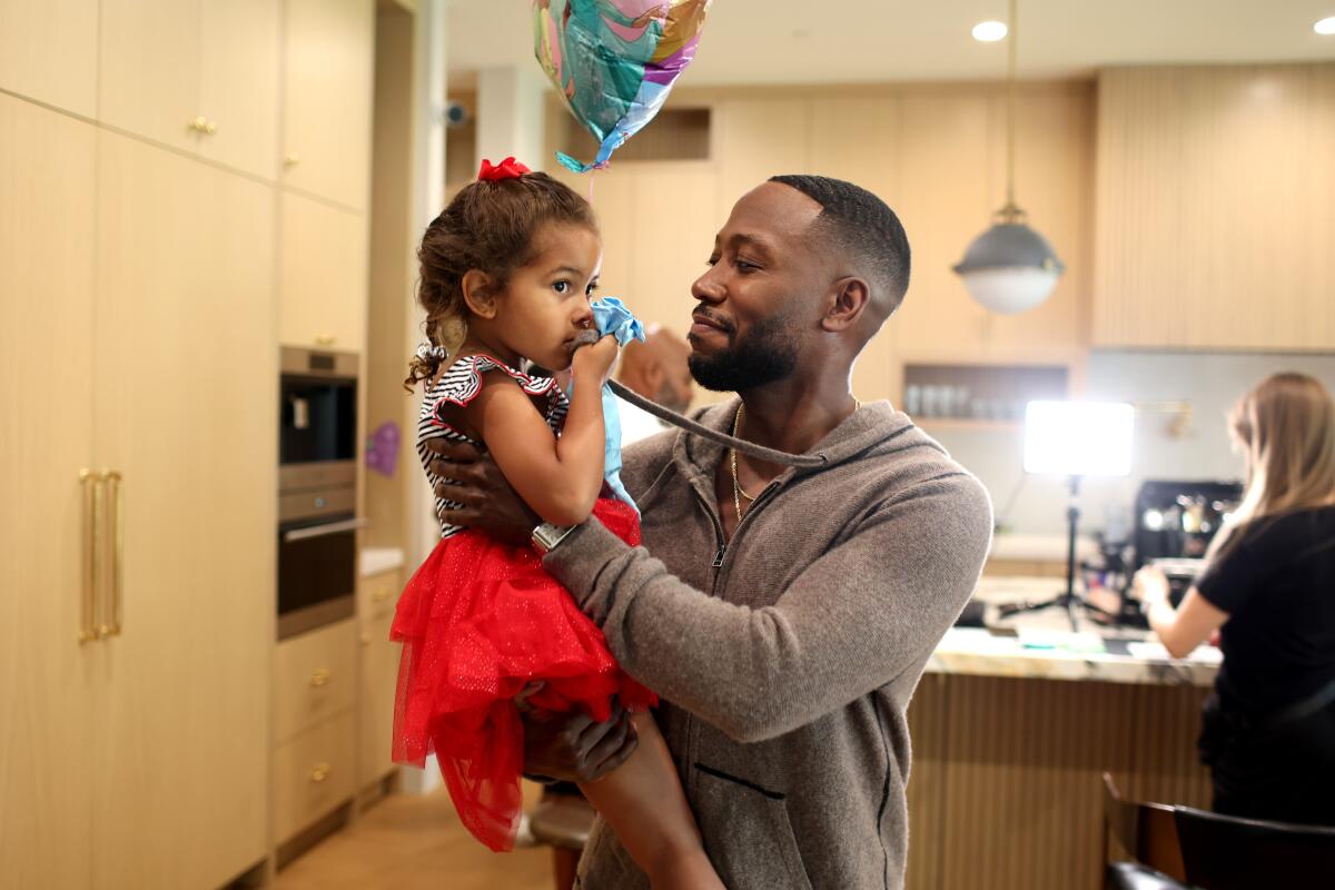 Lamorne Morris holds his 4-year-old daughter in his kitchen