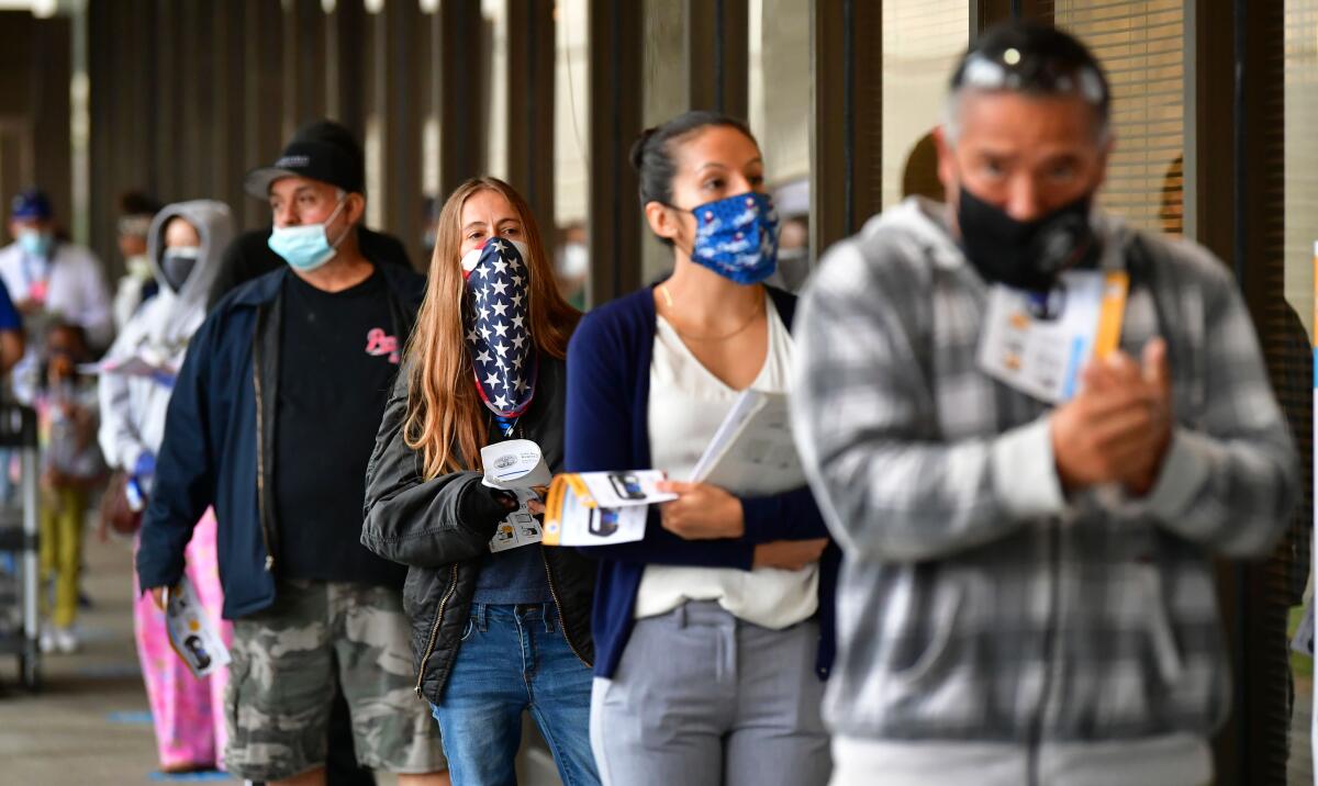 Voters wear face coverings while waiting in line to vote in the 2020 U.S. elections 