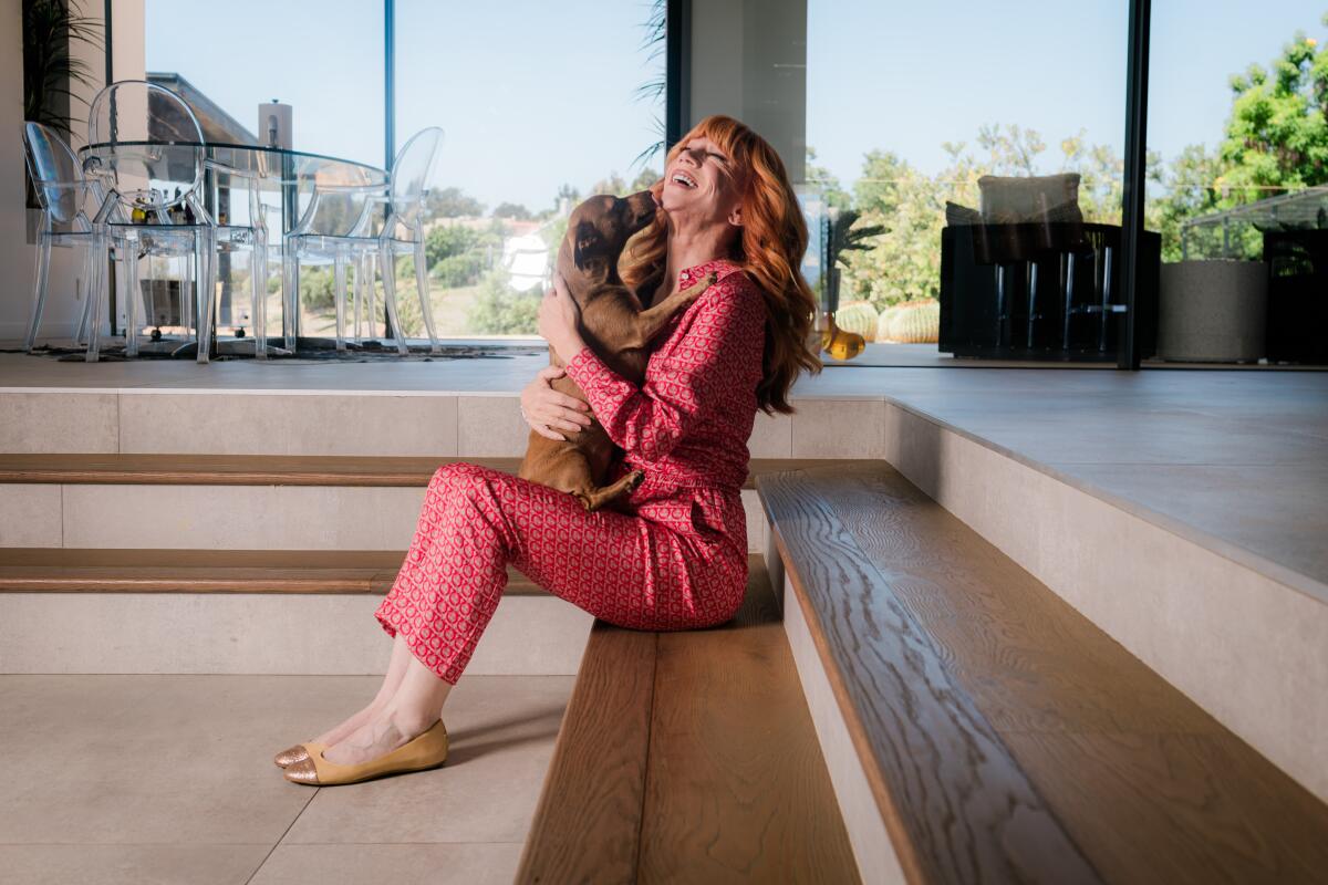 Woman holding her dog on a set of indoor steps