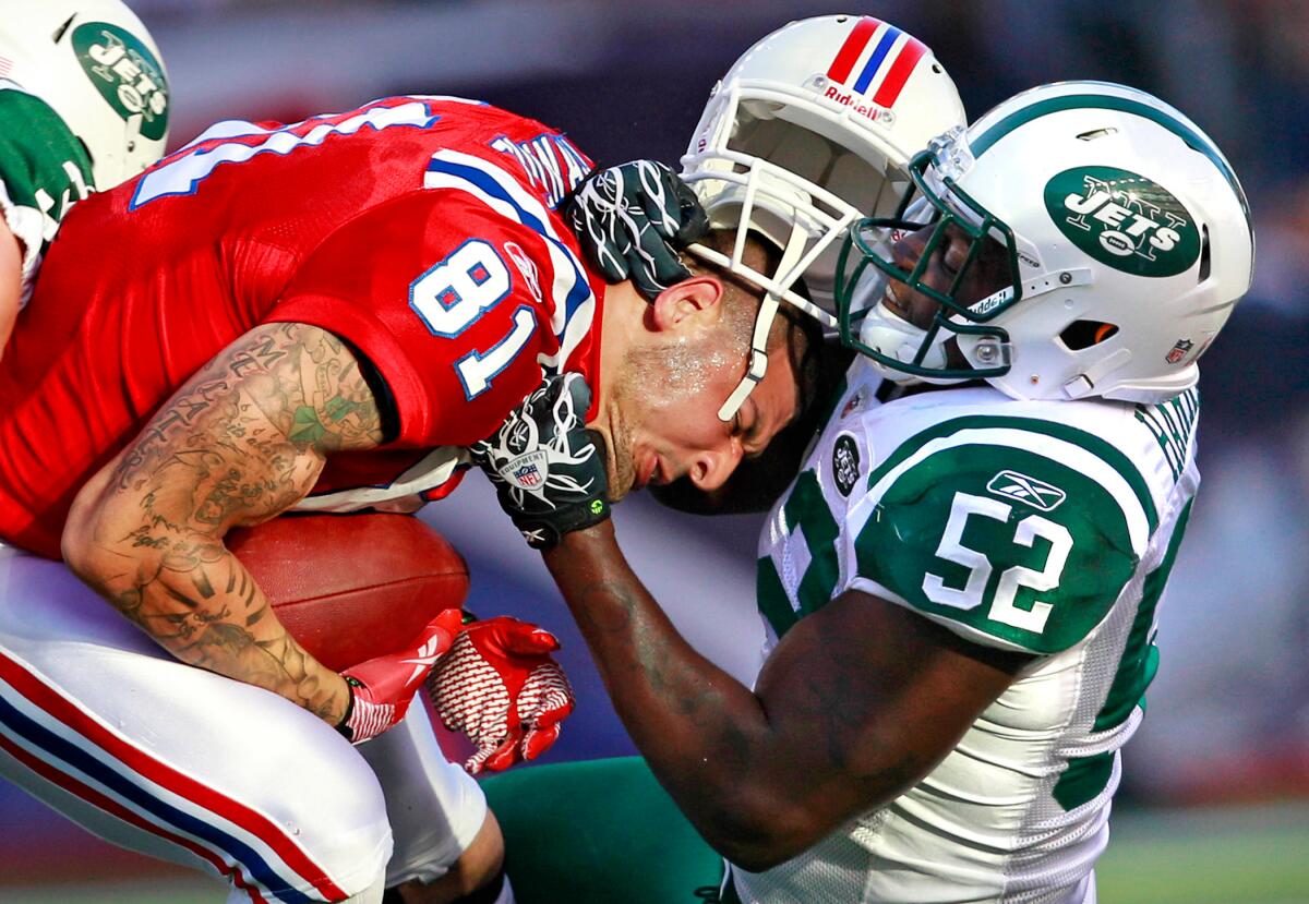 A football player, his  white helmet sitting on top of his head, tackles into the chest of another football player.