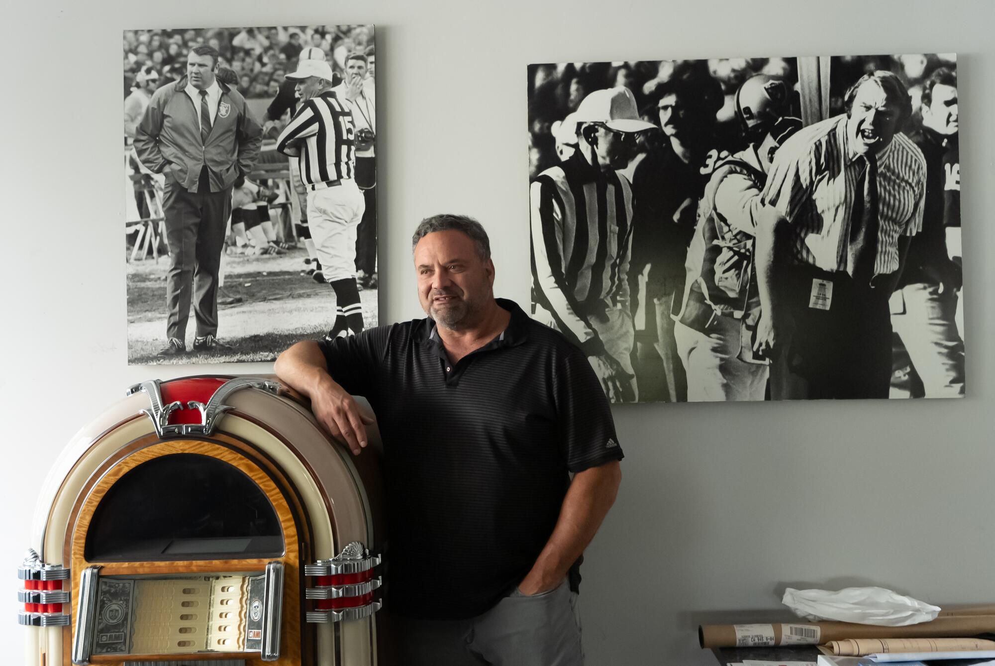 Joe Madden rests his elbow on a jukebox next to enlarged photos from his father's career.